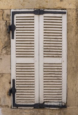 Closed white shutters in a house in France.