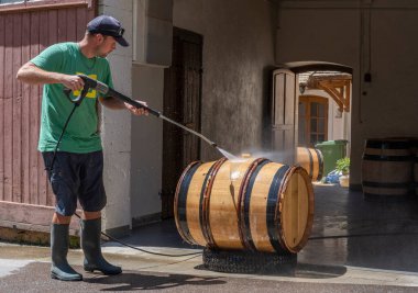 Monthelie, France - June 30, 2020: Cleaning wine barrels on the street in front of the clos in Monthelie in burgundy with pressure washer, France.