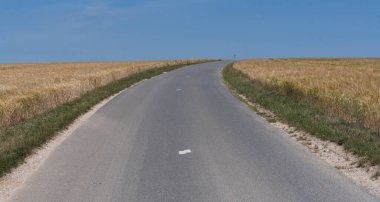 Fransa 'nın kuzeyinde mavi gökyüzü olan buğday tarlasında yol.