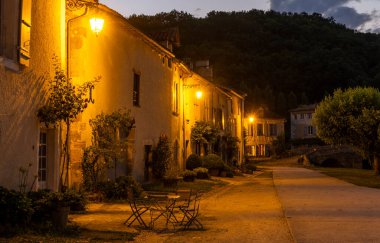 Saint-Jean-de-Cole köyünde geceleri sandalye ve masa olan küçük bir sokak. 