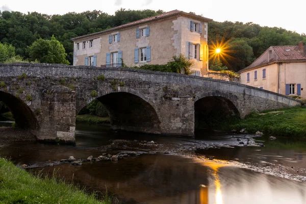 Small river La Cole with houses with blue shutters and an old bridge in the evening in the village of Saint-Jean-de-Cole one of the \'Plus beaux village de France\'.