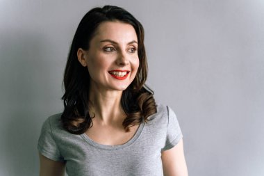 Yakından bakınca, gri arka planda gülümseyen bir kız. Kırmızı dudakları var..