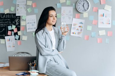 Güzel, genç bir bayan işe giderken suyun önünde, masanın üzerine yaslanıyor. İlgi kavramı, ofiste çalışmak..