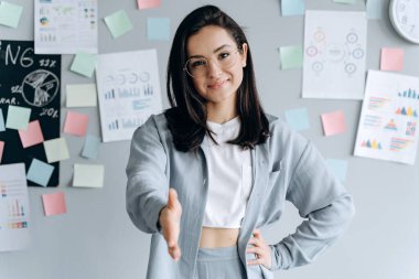 Güzel iş kızı ofiste merhaba demek için elini uzatıyor. Ofiste gülümseyen esmer.