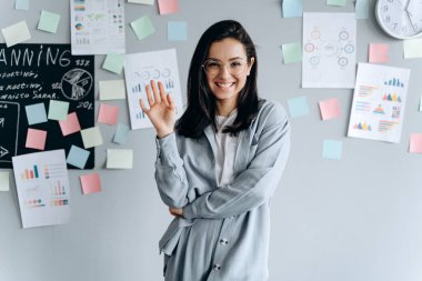Gri duvar arkasında poz veren çekici, tatlı esmer. Çalışma alanı, ofis, planlama ve geliştirme kavramı.