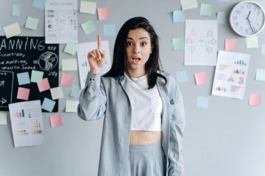 Düşünen kadının bir fikri var. Başını kaldır ve parmağını kaldır. Gri arkaplanda izole