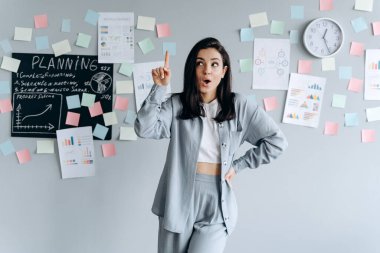 Düşünen kadının bir fikri var. Başını kaldır ve parmağını kaldır. Gri arkaplanda izole