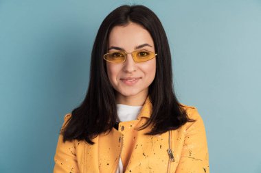 Güneş gözlüklü güzel, çekici bir kız mavi arka planda izole edilmiş. Kopya boşluğunda genç bir kadın, metin için yer.