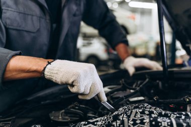 Beyaz erkek tamirci garajda araba tamir ediyor. Araba bakımı ve oto servis garajı konsepti. Yakın el ve anahtar. 