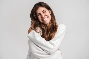 Ben egoistim, kendimi severim. Dalgalı saçlı, bencil narsist genç kız kendini kucaklıyor ve hayal gibi bir ifadeyle gülümsüyor. Beyaz arka planda izole edilmiş kapalı stüdyo görüntüleri 