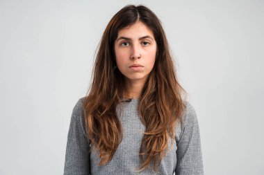 Kameraya bakan ciddi bir kadının portre görüntüsü kendinden emin, odaklanmış ve kendinden emin hissediyor. Beyaz arka planda izole edilmiş kapalı stüdyo görüntüleri