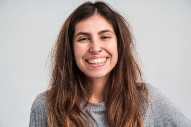 Gülümseyen kadın portresi pozitif duyguları ve mutluluğu ifade ederken kameraya bakıyor ve iyi bir ruh hali içinde. Beyaz arka planda izole edilmiş kapalı stüdyo görüntüleri