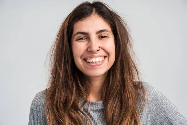 Gülümseyen kadın portresi pozitif duyguları ve mutluluğu ifade ederken kameraya bakıyor ve iyi bir ruh hali içinde. Beyaz arka planda izole edilmiş kapalı stüdyo görüntüleri