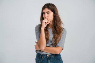 Hmm, bir düşüneyim. Memnun, kafa karıştırıcı bir kavram. Sıradan giyinmiş bir kadın, başka tarafa bakıyor, çenesine dokunuyor ve düşünüyor. Stüdyo çekimi 