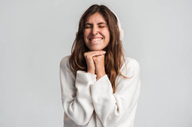 Neşeli kadının stüdyodaki görüntüleri gözlerini kapadı ve beyaz stüdyo arka planında izole edilmiş kulaklıklarla en sevdiği müziği dinlerken zaferle bir şeyler kutladı. 