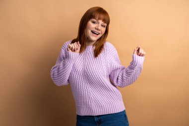 I'm winner. Portrait of ecstatic overjoyed lady dancing with raised arms, smiling excitedly, celebrating victory, success. Indoor studio shot isolated on orange background 