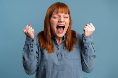 Shocked surprised woman rejoicing and open mouth, sees astonishing things. Indoor studio shot isolated on blue background 