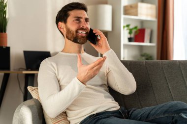 Man sitting at his workplace and chatting at the smartphone while working remotely from home. People and technologies concept 