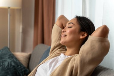 Huzurlu, sakin, genç bir kadın. Kanepede dinleniyor. Huzurlu bir ruh hali içinde başka yere bakıyor ve dinleniyor. Stok fotoğrafı