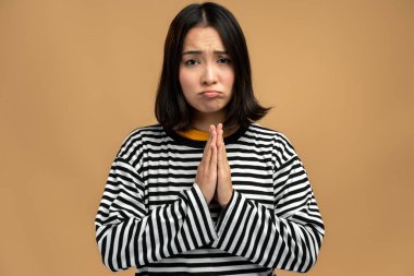 Lütfen, affınıza sığınıyorum. Üzüntülü bir kadının portresi umutsuz bir şekilde suratını buruşturup yardım için dua ediyor, özür diliyor. Stüdyo çekimi bej arkaplanda izole edildi