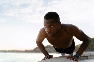 Egzersiz. Sağlıklı, kaslı vücudu olan, şınav çeken sağlıklı, aktif bir adam. Sportif atletik erkek plajda egzersiz yapıyor, açık havada antrenman yapıyor. Spor ve spor konsepti 