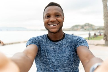 Yakışıklı bir adam eğitiminden sonra selfie çekiyor ya da görüntülü görüşme yapıyor. Mutlu Afro-Amerikan erkeği kameraya gülümsüyor 