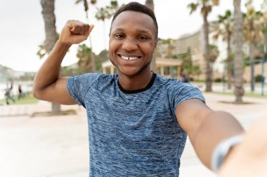Mutlu, neşeli, gülümseyen erkek kişinin suda selfie çekmesi. Okyanustaki eğitimden sonra sahilde durup kameraya gülen mutlu bir adam. 