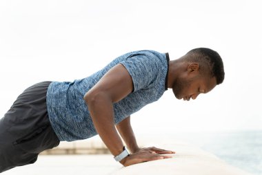 Egzersiz. Formda kaslı vücudu olan ve şınav çeken sağlıklı, aktif bir adama yakın çekim. Sportif atletik erkek plajda egzersiz yapıyor, açık havada antrenman yapıyor. Spor ve spor konsepti 