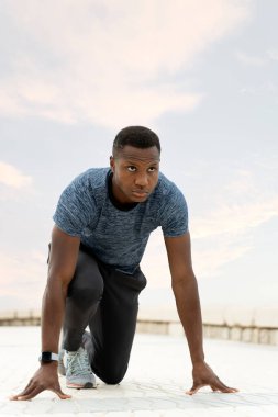 Afrika kökenli Amerikalı sporcuların bulutlu bir gökyüzüyle plajda koşup zıplamaya hazırlanışlarını uzun uzun görüyoruz. Spor ve eğlence konsepti 