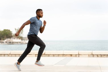 Genç atletik ve formda Afro-Amerikan sporcunun plajda antrenman yapmasının yan görüntüsü. Erkek antrenmanı ve koşu. Sağlıklı yaşam tarzı kavramı 