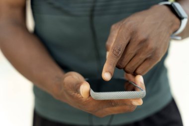 Melez ırk adamının sokakta dikilirken akıllı telefonuna müzik açtığı görüntüler. Teknoloji ve insanlar kavramı