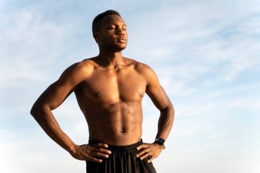 Siyah plaj şortlu, Afro-Amerikan kaslı genç adam parlak plajda güneşleniyor. Güzel yaz havası. Stok fotoğrafı 
