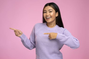 Neşeli kadın parmağındaki fotokopi alanını işaret ediyor. Fikir sunumu için boş bir yer. Ürün reklamcılığı. Pembe arka planda kapalı stüdyo çekimleri 