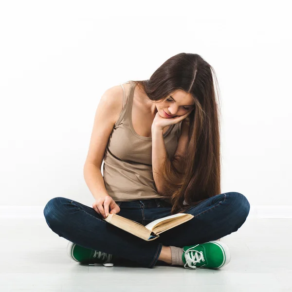 Schöne junge Frau sitzt mit Buch auf dem Boden — Stockfoto