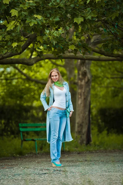 Muito atraente jovem posando em jeans e casaco azul ao ar livre no verão.Parque de tiro ao ar livre — Fotografia de Stock