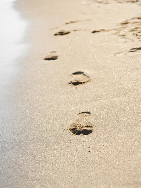 Impressões de pé na areia no nascer do sol de verão na praia tropical — Fotografia de Stock