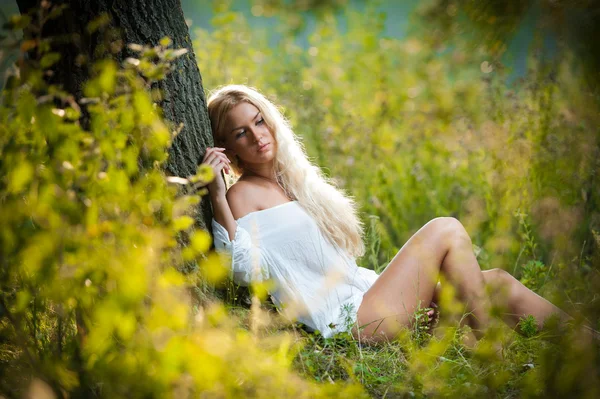 Menina loira muito jovem em vestido branco sentado na grama — Fotografia de Stock