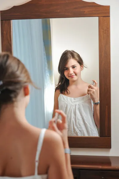 Una hermosa adolescente estudia su apariencia mientras se mira en el espejo a su hermoso reflejo joven. Adolescente chica feliz con su apariencia en el espejo — Foto de Stock
