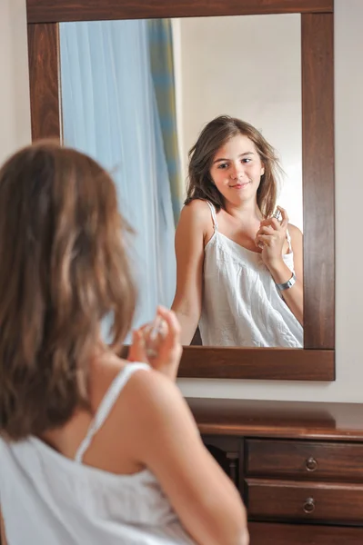 Una hermosa adolescente estudia su apariencia mientras se mira en el espejo a su hermoso reflejo joven. Adolescente chica feliz con su apariencia en el espejo — Foto de Stock