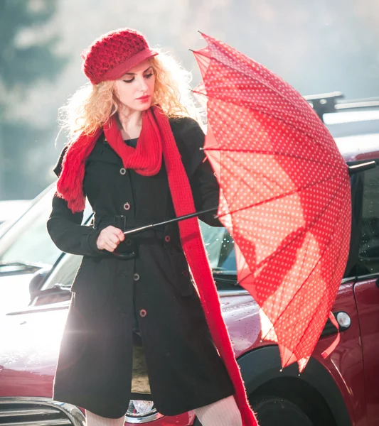 .Beautiful fashionable young girl with red umbrella in the street — Stock Photo, Image