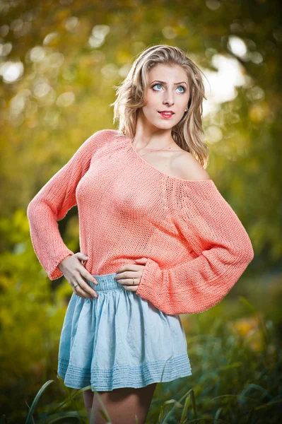 Sexy donna elegante con camicia rosa seduta sull'erba nel parco autunnale. Giovane bella donna al parco autunnale. Bella donna con camicia rosa trascorrere del tempo nel parco durante la stagione autunnale  . — Foto Stock