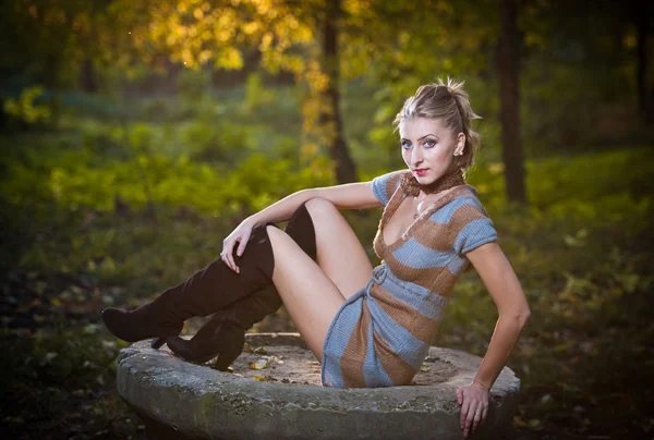 Schöne sexy Mädchen mit langen Lederstiefeln und kurzem Kleid posiert im Park im Herbst day.beautiful elegante Frau im Herbst park .young hübsche Frau mit langen Beinen im Wald. — Stockfoto