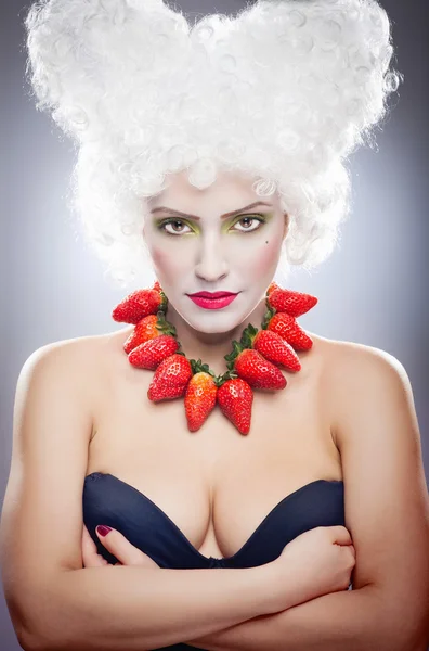 Creative makeup beauty shot of model with strawberries, artistic edit .Woman with strawberry necklace, wig and makeup professionally posing in studio — Stock Photo, Image