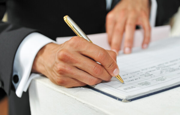Business man signing a contract on a white table.