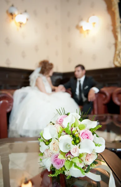 Los detalles de la boda - los matrimonios jóvenes detrás del ramo de boda en la habitación — Foto de Stock