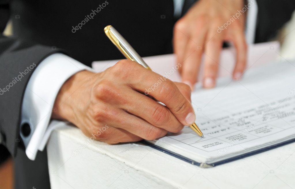 Business man signing a contract on a white table.