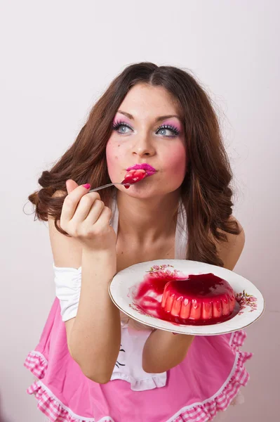 Привлекательная молодая довольная женщина ест пудинг на белом фоне  . — стоковое фото