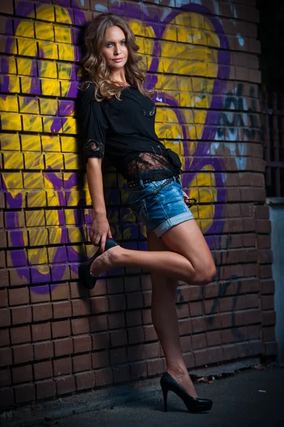 Schoonheid meisje poseren mode in de buurt van rode bakstenen muur op de straat .young vrouw met zonnebril tegen een muur met graffiti — Stockfoto