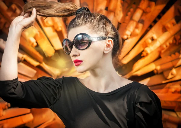 Μοντέρνο ξανθιά κοπέλα σε γυαλιά ηλίου στη γυναίκα background.hot χρώμα σε γυαλιά ηλίου με μακριά μαλλιά στο φως και κόκκινο φόντο με υφή — Φωτογραφία Αρχείου