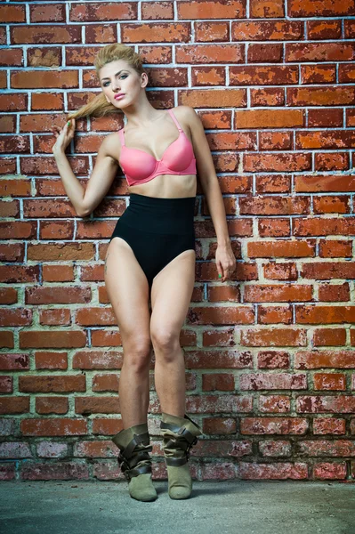 Girl in swimsuit posing provocatively in front of a brick wall.young model posing in front of Brick wall.Posing pretty.Beautiful model standing near red brick wall — Stock Photo, Image